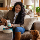 Woman feeding dental powder to dog